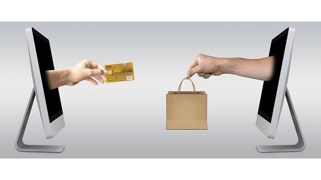 Two computer screens depict a digital transaction with a hand offering a credit card and another hand receiving a shopping bag.