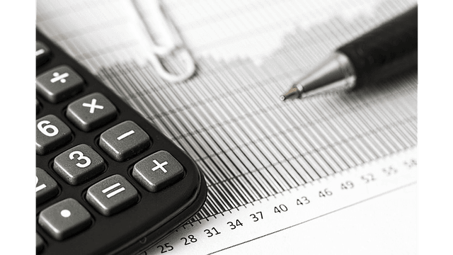 A calculator, pen, and ruler on a printed graph paper.